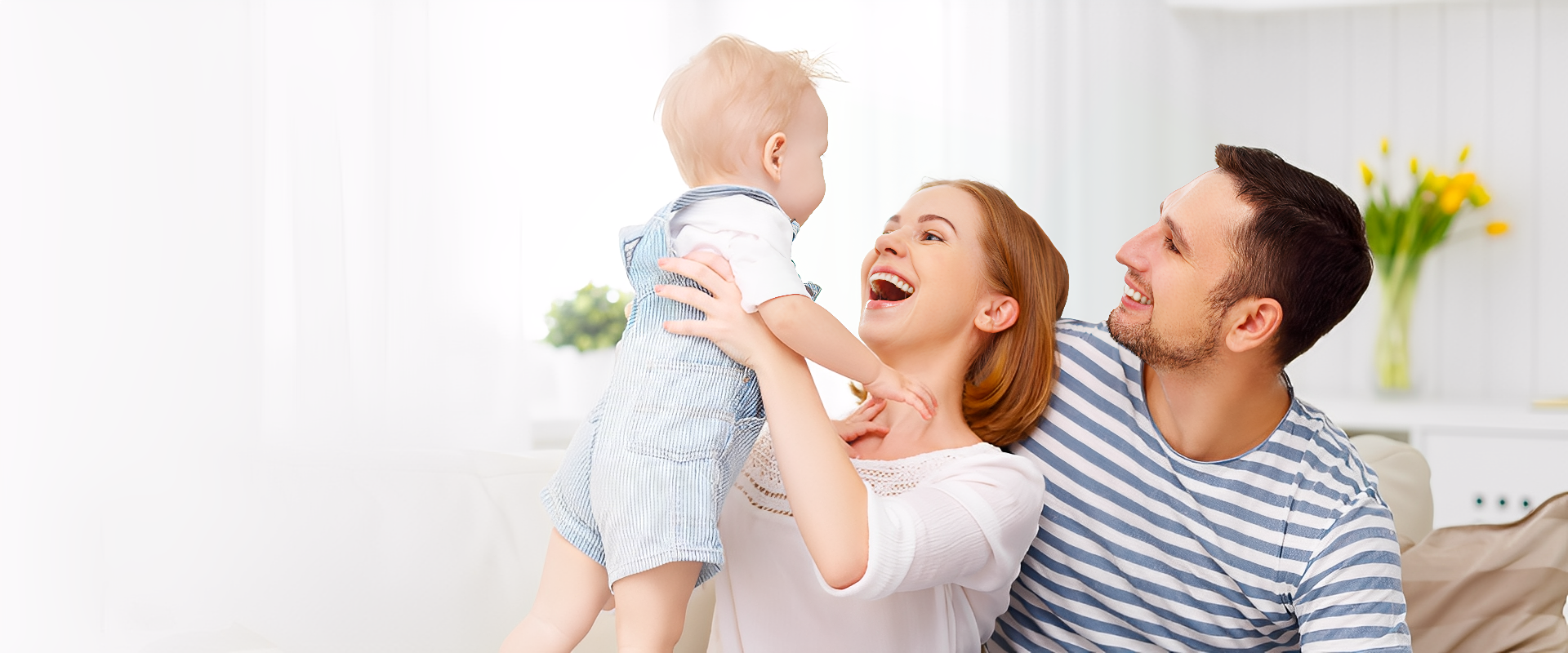Happy family playing with their baby indoors.